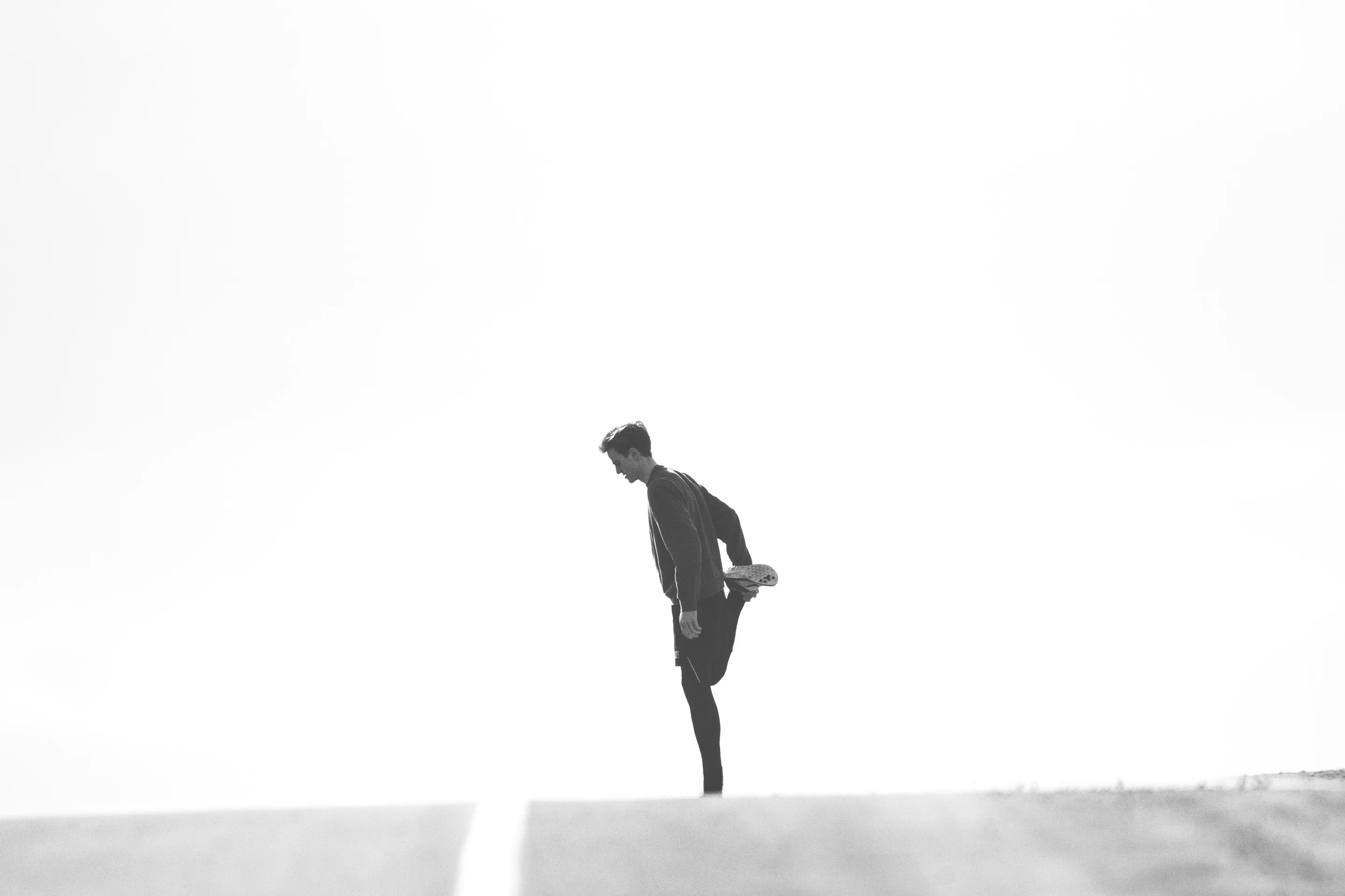 A runner stretching on an empty road before a run